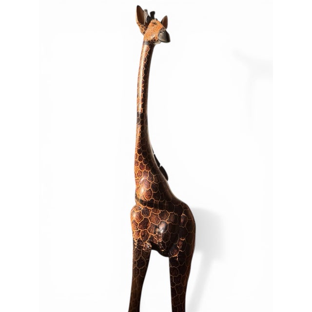 Large hand-carved wooden giraffe with elongated proportions and a richly hand-painted surface. Likely African or African-...