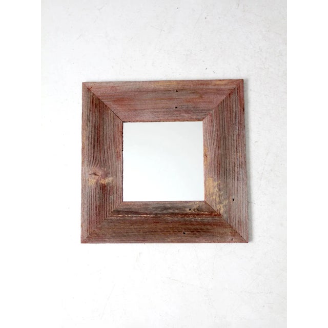 This vintage wall mirror features a rustic barn wood frame in a naturally faded red tone. The weathered finish and simple...
