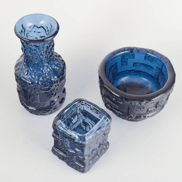 Mouth-blown sculptural glass vases in rich cobalt blue with pronounced ice-textured relief — one tall cylindrical vase,...