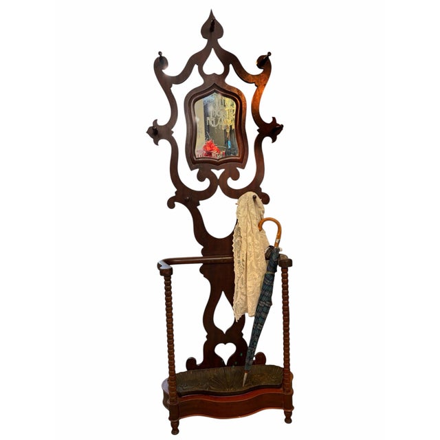 A striking Victorian hall tree with a dramatic, sculptural silhouette, original mirror, and gracefully shaped arms...