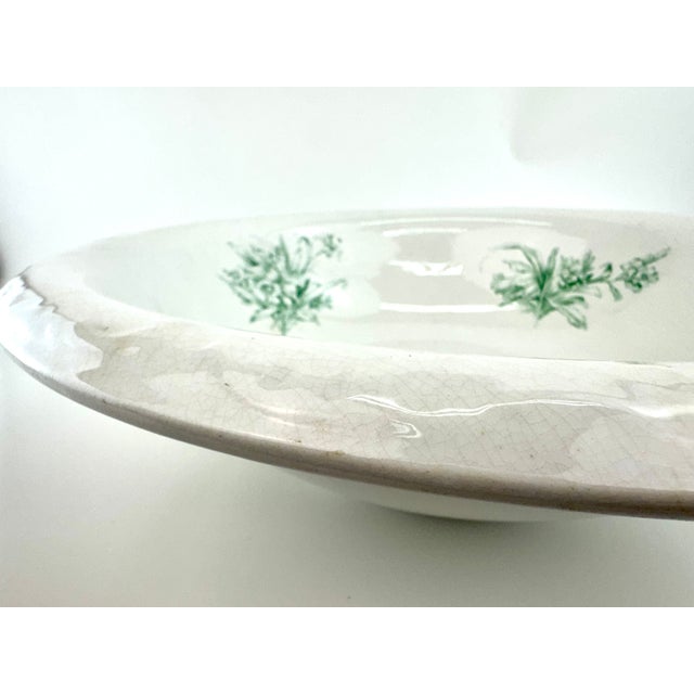 Antique French Digoin serving bowl featuring soft green floral transfers against warm ivory ironstone with beautiful age-...
