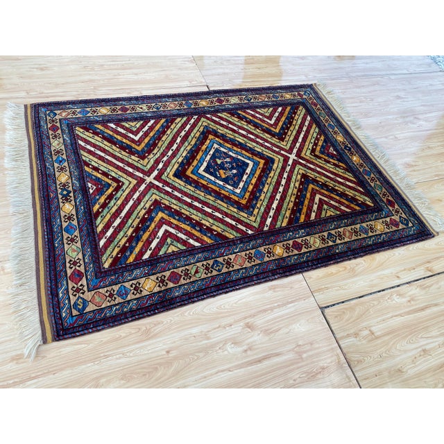 This vintage rug is hand-knotted in wool, woven in the Kazak Caucasian tribal design tradition, in a sunburst pattern of...