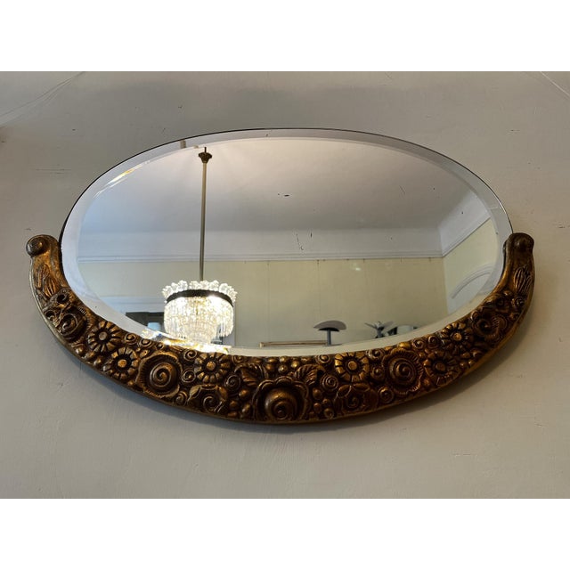 The Art Deco wall mirror is attached to the wall using two eye screws or a cord. It consists of a gold-colored wooden...