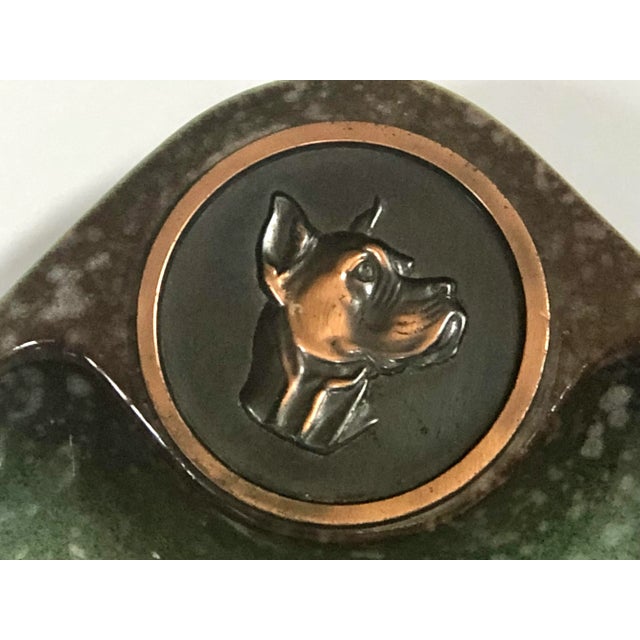 Different than most of these Rookwood ashtrays that have a monogram copper medallion, this one has the image of a dog’s...