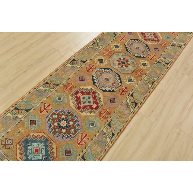 A tribal Caucasian Kazak runner hand-knotted with fine wool on a cotton foundation. This rug features a row of geometric...