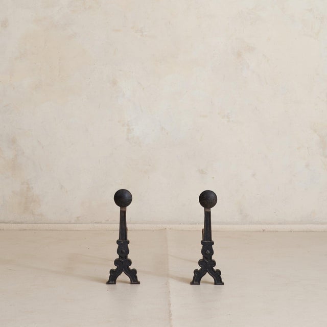 A pair of French wrought-iron andirons from the 1930s, well-scaled with a grounded presence. Each is formed with a...