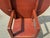 A charming round flip-top dining table finished in a warm, muted red with an intentionally distressed surface in the folk-...