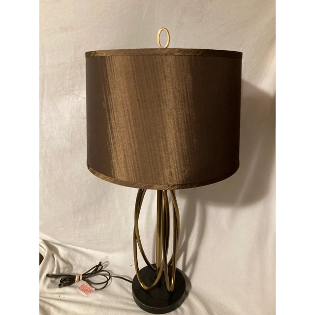 Abstract brass hoop design sit on a black base. Has a three way dimmer switch. Comes with beautiful shimmering brown...