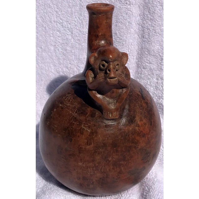 A charming mold-formed pottery vessel with a planar base, a spherical body with a bulbous shoulder, a stirrup-shaped...