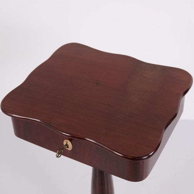 Antique sewing table / lamp table crafted in mahogany with a column base, three feet, and a lock. Dating from the 20th...