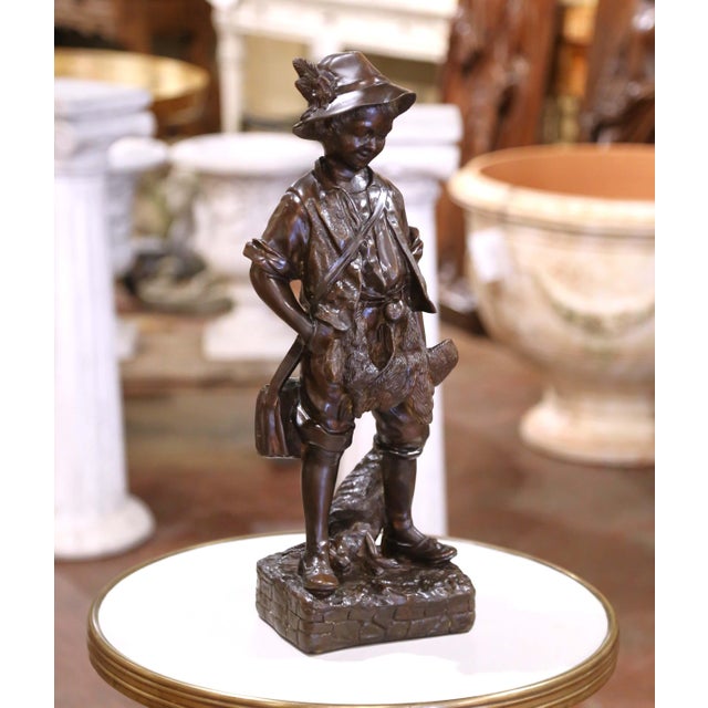 This charming mid-century French bronze sculpture depicts a young hunter in rustic attire, modeled in the sentimental and...