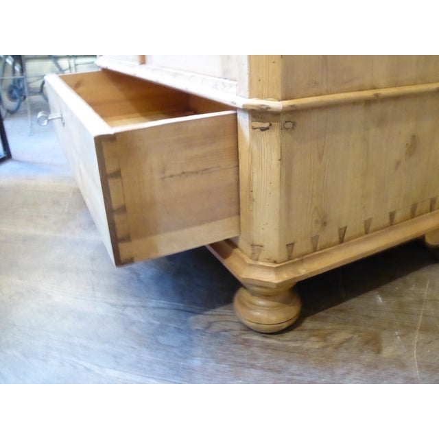 This pine armoire has three adjustable shelves, a lower, dove-tailed drawer, an upper faux drawer and bun feet. The door...