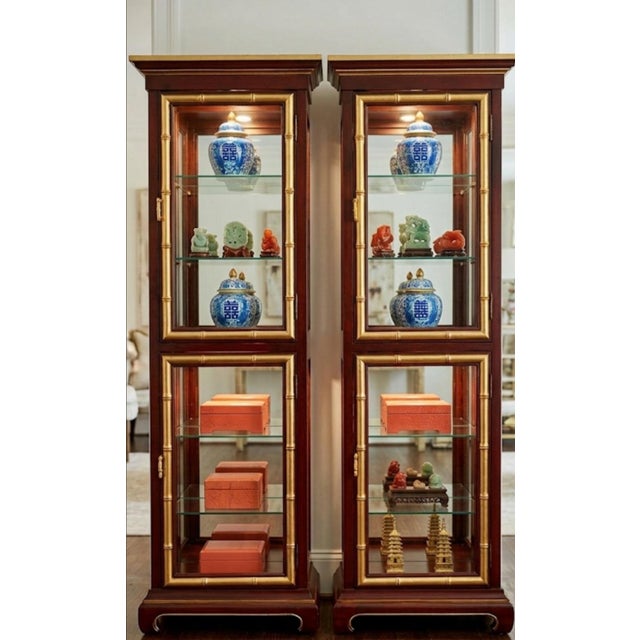 An incredible pair of Vintage faux bamboo ming base glass etagere cabinets in the style of Jasper. The cabinets are well...