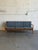 This Model 56 three-seater couch features an elegant open frame with softly curved armrests and an angled back profile....