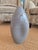 A light gray Barbini Murano gray vase. It is in an oblong shape with dips on both sides of the vase. The opening at the...