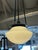 Oil-rubbed bronze pendant with a round opal glass bowl shade. The shade is suspended from a circular ceiling canopy by...