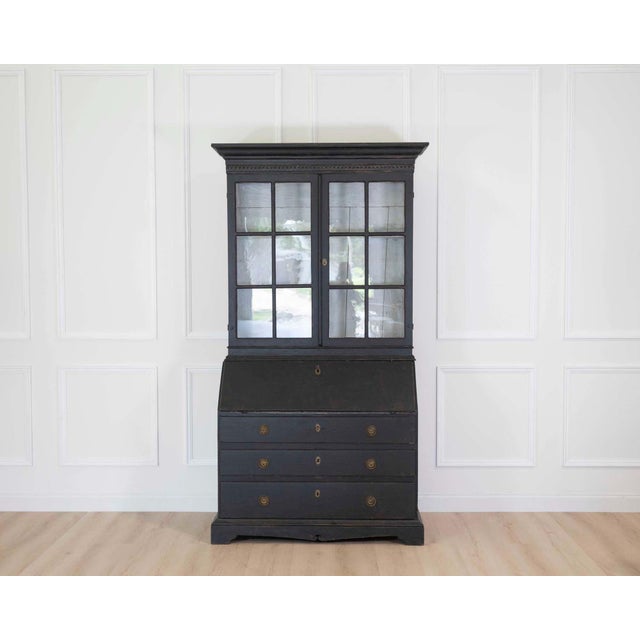 A beautifully crafted Swedish Gustavian style secretary vitrine finished in hand-painted black with a softly aged...