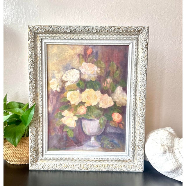 A charming mid-century oil painting depicting a lush arrangement of ivory, peach, and pale yellow roses gathered in a...