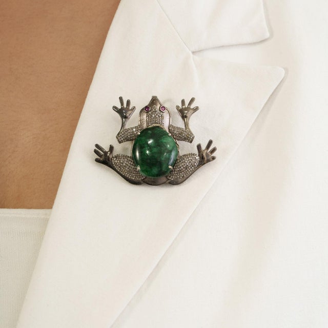 The Antique-Style Oxidized Silver Emerald, Ruby & Diamond Frog Brooch Pendant showcases a distinctive figural design...