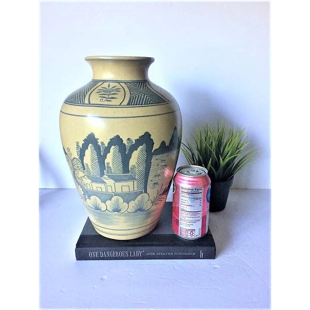 This is a lovely, large ceramic vase. The vase is natural colored pottery, with dark blue artwork. The art on one side of...