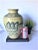 This is a lovely, large ceramic vase. The vase is natural colored pottery, with dark blue artwork. The art on one side of...