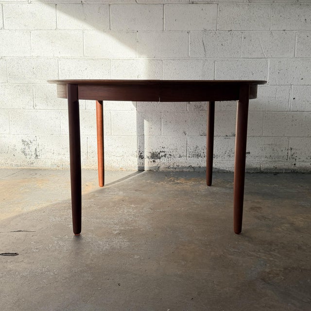 A vintage Danish round teak dining table dating to the 1960s, with a broad circular top, softly rounded edge, and four...