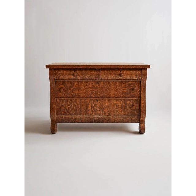 Showcasing the striking grain of tiger oak, this antique dresser features a classic serpentine front, four spacious...