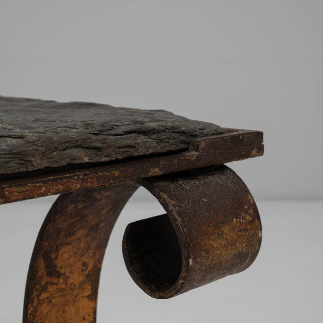 This 1940s French metal coffee table features a striking interplay of sculptural form and rugged materials, creating a...