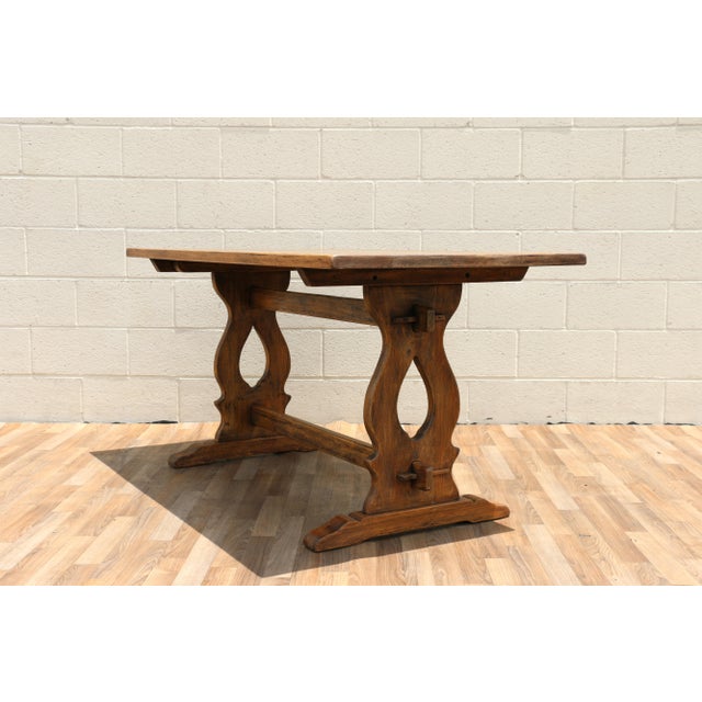 Beautiful antique American trestle dining table dating to the 1930s, featuring a solid oak top and a richly toned cherry...