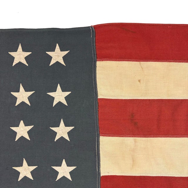 This vintage American flag is made from a cotton cloth with fully sewn stars and stripes. Please note overall staining,...