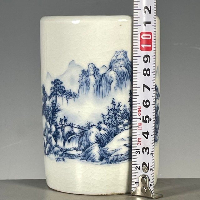 A charming Chinese blue and white porcelain brush pot (bitong). The cylindrical vessel features a creamy, all-over crackle...