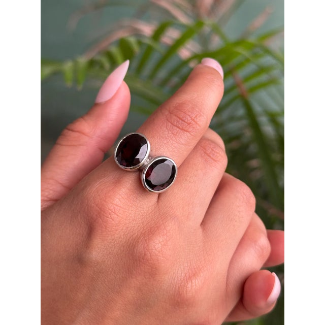 This elegant two-stone ring is crafted from 925 Sterling Silver and features the timeless beauty of oval-cut garnets. Each...