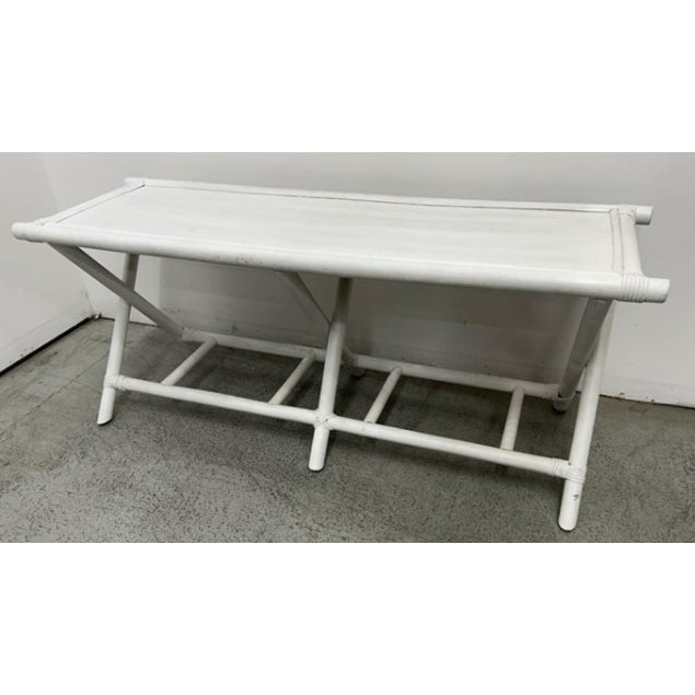 A stylish Hollywood Regency bench featuring a white-painted rattan frame with classic wrapped joint details and elegant...