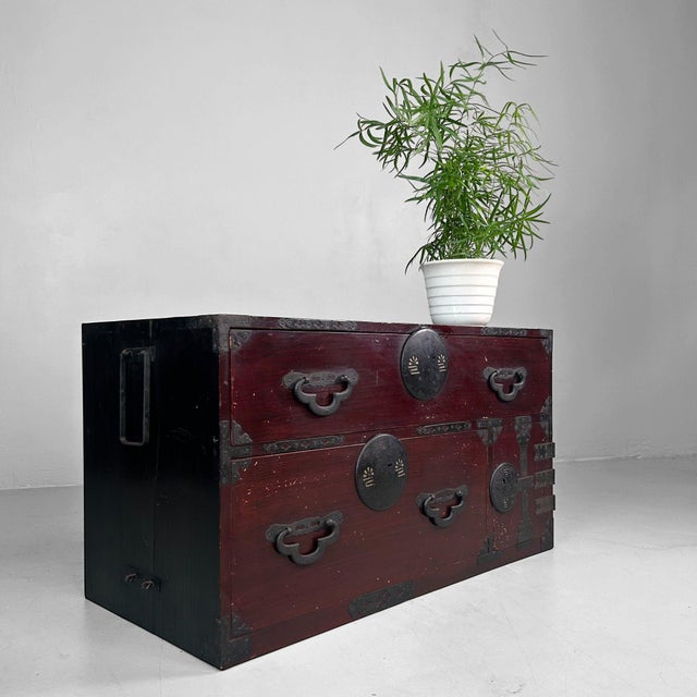 An elegant Japanese tansu from the Meiji period (ca. 1900), featuring a rich reddish-brown lacquer finish and beautifully...