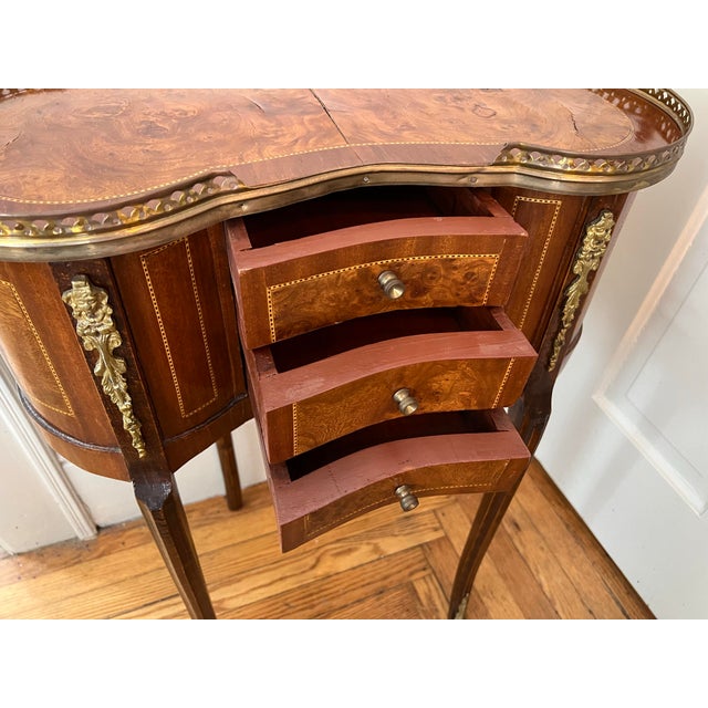 This charming French style kidney shaped side table with three drawers is furnished with brass handles, feet and...