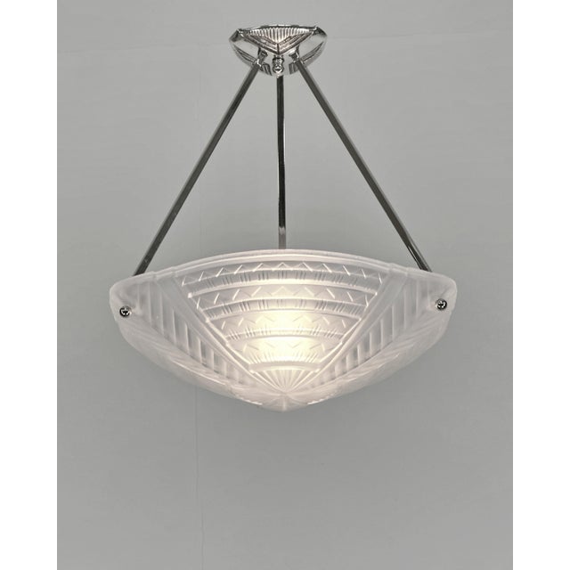 NOVERDY A French 1925-1935 art deco pendant light in nickel plated solid brass holding a bowl in clear frosted molded-...