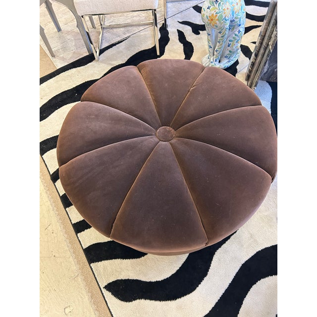 Luxurious brown velvet round ottoman pouf with gorgeous channelled upholstery emanating from central button on top. CD...