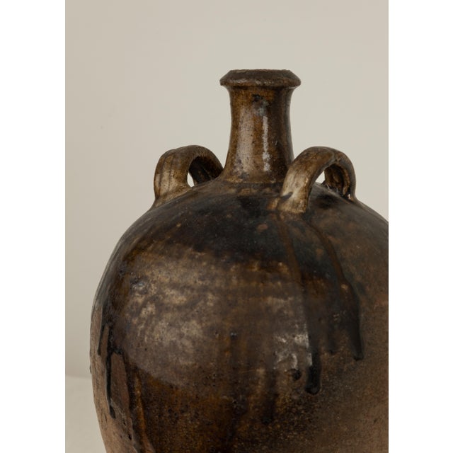 19th Century French Provincial stoneware jug with central spout, twin size handles and drip manganese glaze.