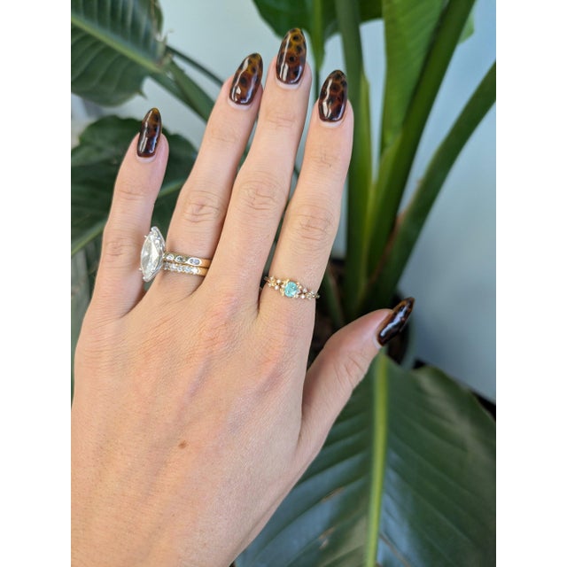 A 0.28-carat blue paraiba tourmaline oval sits at the centre of this solid 14K yellow gold ring, framed by ten earth-mined...
