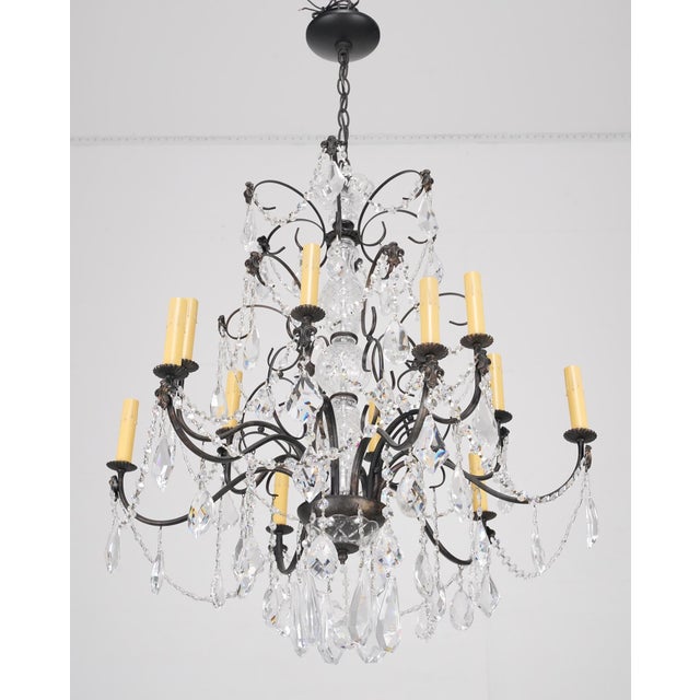 French style chandelier made of faceted teardrop and octagon shaped crystals paired with a black painted steel frame and...