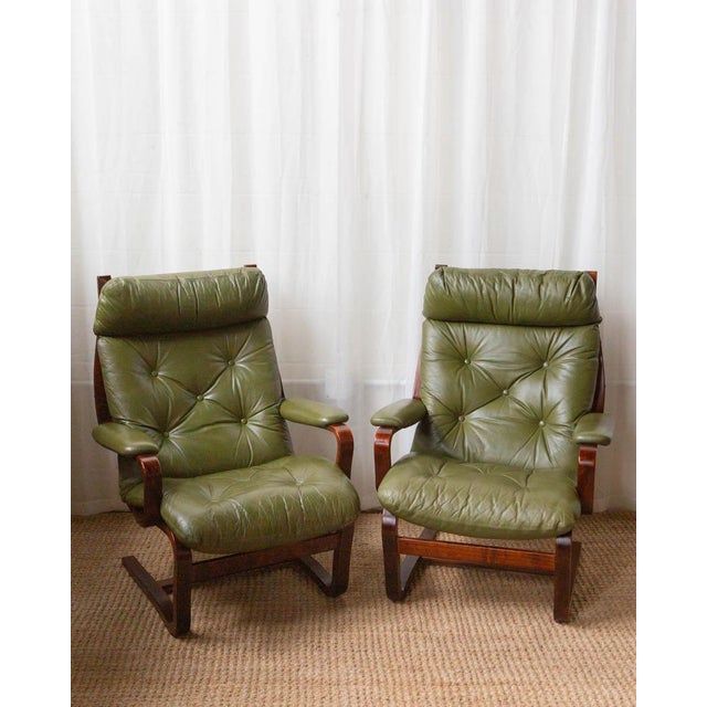 A pair of Westnofa-style lounge chairs featuring sculptural bent beechwood frames and supple green leather upholstery. The...