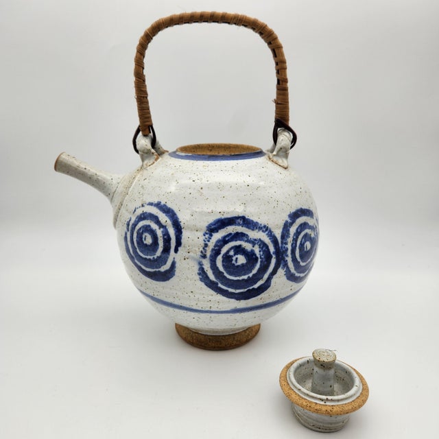 great round tea pot with circle motif. thin spout with cane handle