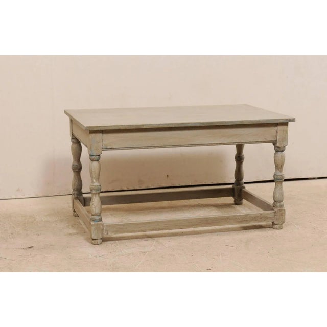 A French grey-toned wood coffee table from the mid-20th century. This vintage French coffee table of wood features a...