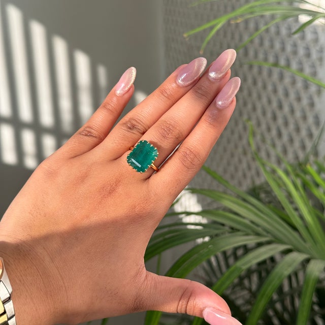 This striking 9.08-carat emerald-cut emerald solitaire ring is crafted in 18K yellow gold. The emerald, measuring about 15...