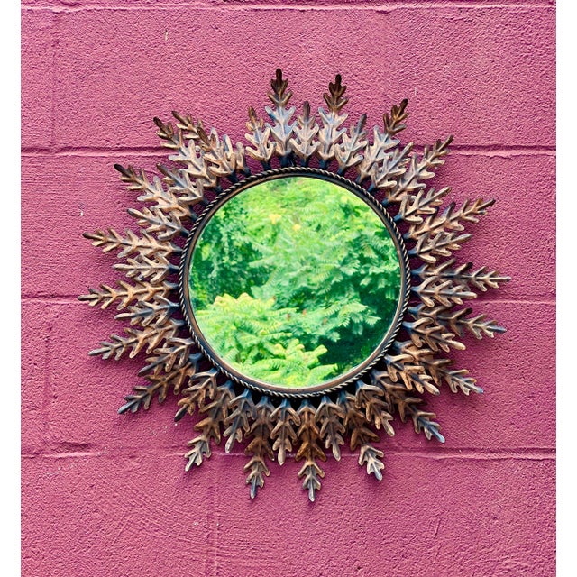 This beautiful 1950s Spanish gilt metal sunburst mirror features alternating large and small leaves or rays surrounding a...