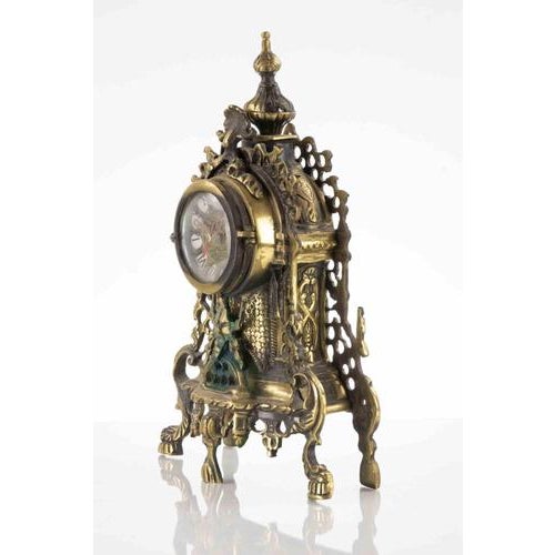 Ancient Victorian table clock, round clock face with Roman numerals and decorative hands, protected by a glass cover. A...