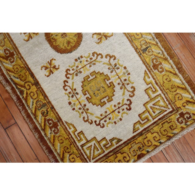 A late 19th century Khotan scatter rug. Field is ivory, gold and brown main accent colors. 1 end border has pops of...