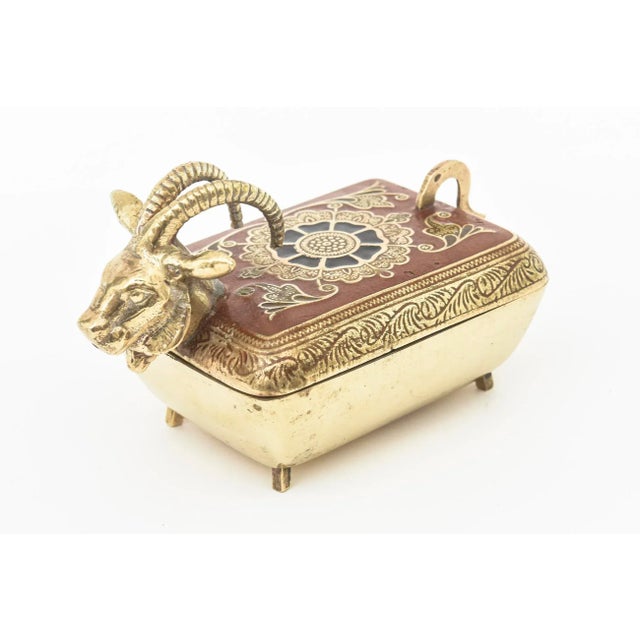 This lovely small mid century modern or 60's brass box is hinged. Very well made. It has the rams head on one end and the...