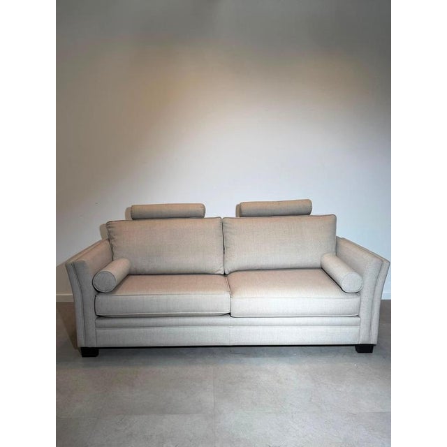 Elegant contemporary three-seater sofa upholstered in a soft neutral beige fabric, combining clean lines with generous...