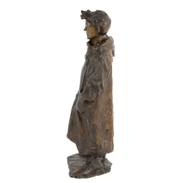 This antique bronze sculpture depicts a youthful figure in a relaxed, animated stance, captured with fine attention to...